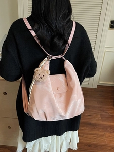 Pink nylon backpack with bear charm and soft moire texture shown on model in home setting