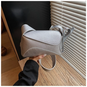 Detail of silver grain leather crossbody bag featuring geometric puzzle flap design