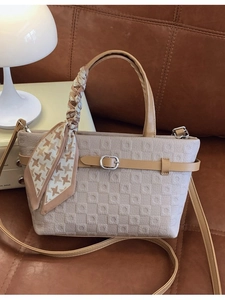 Sac seau élégant avec gaufrage géométrique et foulard en soie sur canapé brun