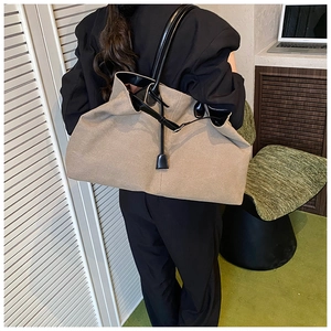 Grande borsa tote in tela kaki con manici in pelle nera portata a spalla per i viaggi