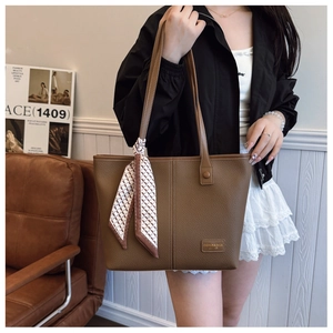 Detailed shot of a brown lychee pattern tote bag with decorative silk scarf on handle