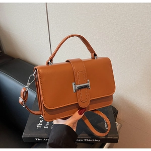 Detailed close-up of a caramel leather handbag with a silver metal clasp and top handle