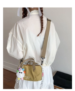 Mustard yellow canvas crossbody bag with cute monster charm shown on a model