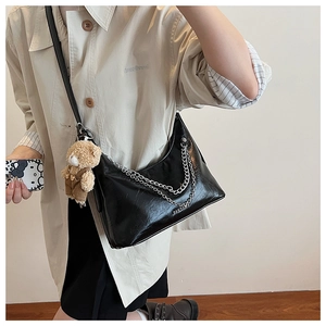 Detailansicht der schwarzen Lackleder-Hobo-Tasche mit Silberketten und Bärenanhänger