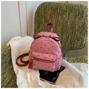 Detailed shot of mini canvas backpack with red stripes, heart patterns and a leather bow