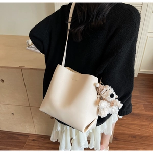 Lifestyle shot of beige bucket bag with plush bear charm on female model