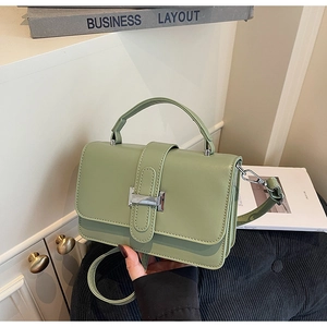 Sage green minimalist crossbody bag with silver buckle on a stylish book backdrop