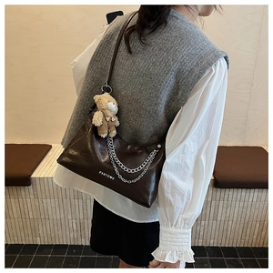 Detail der kaffeebraunen Hobo-Tasche mit Silberketten und einem Plüschbär-Anhänger