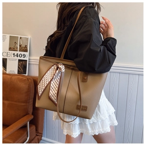 Detail of khaki leather tote bag with silk scarf accessory and litchi grain texture