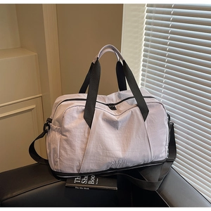 Close-up of light purple travel bag with black straps on a black leather sofa
