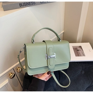 Detail of mint green crossbody bag featuring a silver H-shaped buckle and matte texture