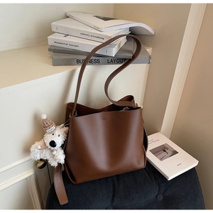 Detail view of brown leather bucket bag with a cute white teddy bear plush charm