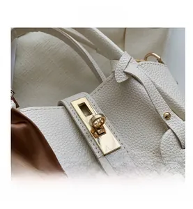 Détail d'un sac à main en cuir grainé blanc avec fermoir doré et foulard en soie marron