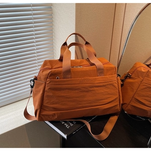Détail du sac fourre-tout en nylon orange avec poignées renforcées et bandoulière