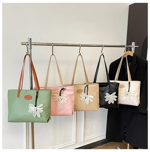 Five assorted colors of elegant PU leather tote bags with floral charms on display