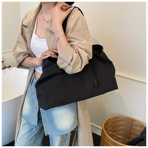 Grande borsa da viaggio in tela nera con dettagli a coulisse indossata da una modella