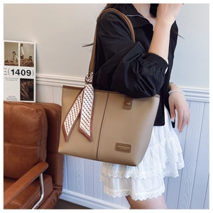 Detail view of brown pebbled leather tote bag with stylish patterned silk scarf on handle