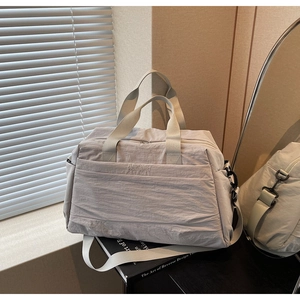 Gros plan d'un sac cabas en toile gris clair avec larges anses et ferrures noir mat