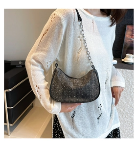 Detail of hobo shoulder bag with sparkling crystals and metal chain strap on a model