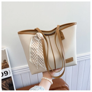 Detail of cream tote bag featuring textured lychee leather and stylish checkered silk scarf