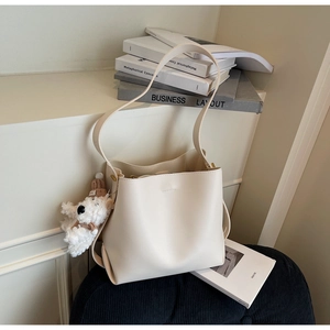 Minimalist cream white leather bucket bag with a cute plush bear charm detail