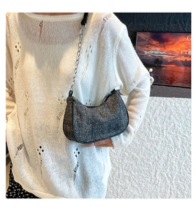 Detail of dark sequined crescent shoulder bag with starry glitter and chain strap