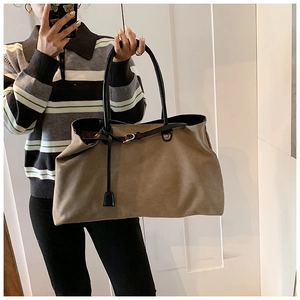 Dettaglio della borsa tote in pelle scamosciata marrone con cinturini in pelle nera