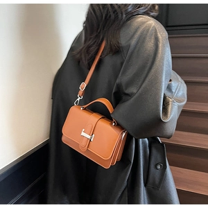 Detail of a brown leather crossbody bag featuring a silver H-shaped metal clasp and strap