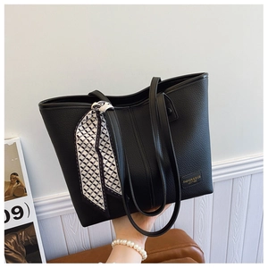 Detail view of black lychee grain leather tote bag with stylish geometric silk scarf detail