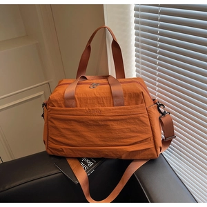Détail du grand sac de voyage orange-brun avec broderie Wellaibag et bandoulière