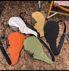 Top view of five colorful oxford fabric crossbody bags displayed on outdoor gravel ground
