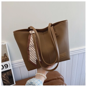 Close-up of brown pebbled leather tote bag with decorative silk scarf and fashion logo