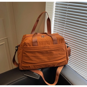 Vue détaillée d'un sac de voyage en nylon orange avec poche zippée et poignées tissées
