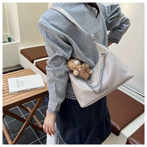 Detail der Hobo-Bag mit Silberkette und Teddybär-Anhänger an der Schulter des Models
