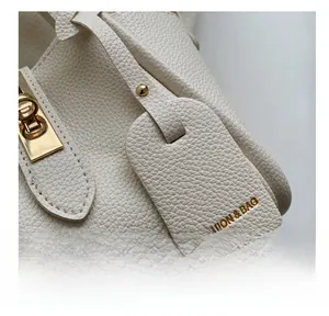 Détail d'un sac en cuir blanc avec fermoir tournant doré et étiquette de mode