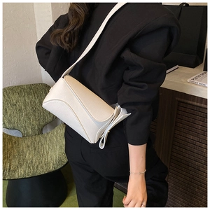 Detail of a white minimalist shoulder bag with lychee texture held by a model