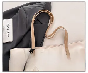 Detail of a beige tote bag with light brown straps and a white mesh flower charm