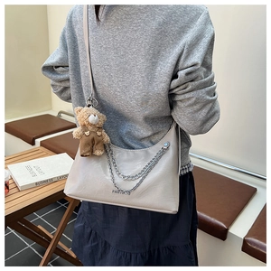 Detail der beige Schultertasche mit Silberketten und einem kleinen Teddybär-Anhänger
