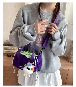 Detail of purple nylon bucket bag with green drawstring interior and cute monster charm