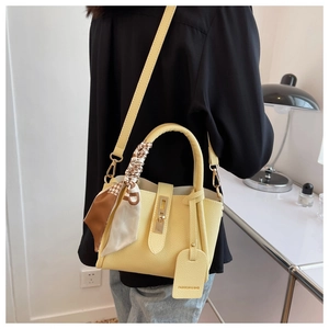 Détail d'un sac seau jaune pâle avec foulard décoratif en soie et fermoir métallique élégant