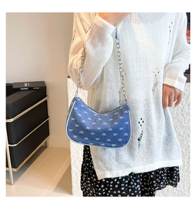 Blue denim hobo bag featuring white bow embroidery and silver chain strap on model