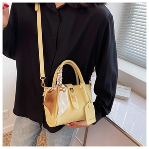 Détail du sac seau en cuir grainé avec foulard en soie et fermoir métallique doré