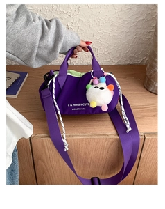 Detail of purple nylon dumpling bag with adjustable strap and cute monster charm