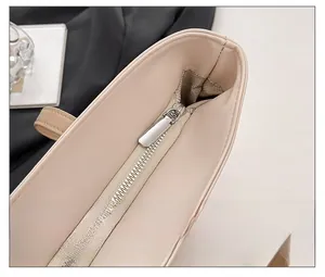 Close-up of smooth silver zipper and gray herringbone lining on beige tote bag