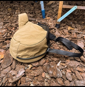 Detail of khaki nylon chest bag showing ripstop texture and black mesh drawstring pocket