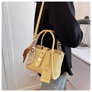 Sac seau en cuir grainé jaune avec foulard en soie porté par une femme à l'épaule