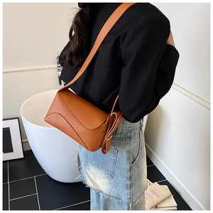 Detail of caramel lychee textured leather crossbody bag with wave side design on a model