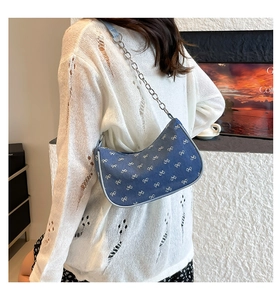 Detail of blue denim hobo bag with white bow patterns and silver metal chain strap