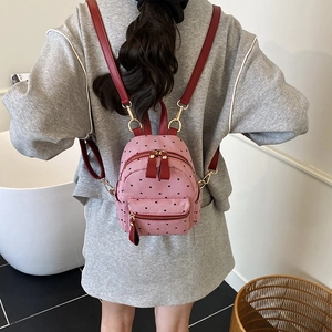 Mini pink striped backpack with red leather straps worn by a woman for travel use