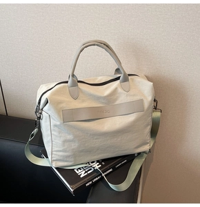 Detail der cremefarbenen Nylontasche mit Lederband, Schultergurt und schwarzem Magazin
